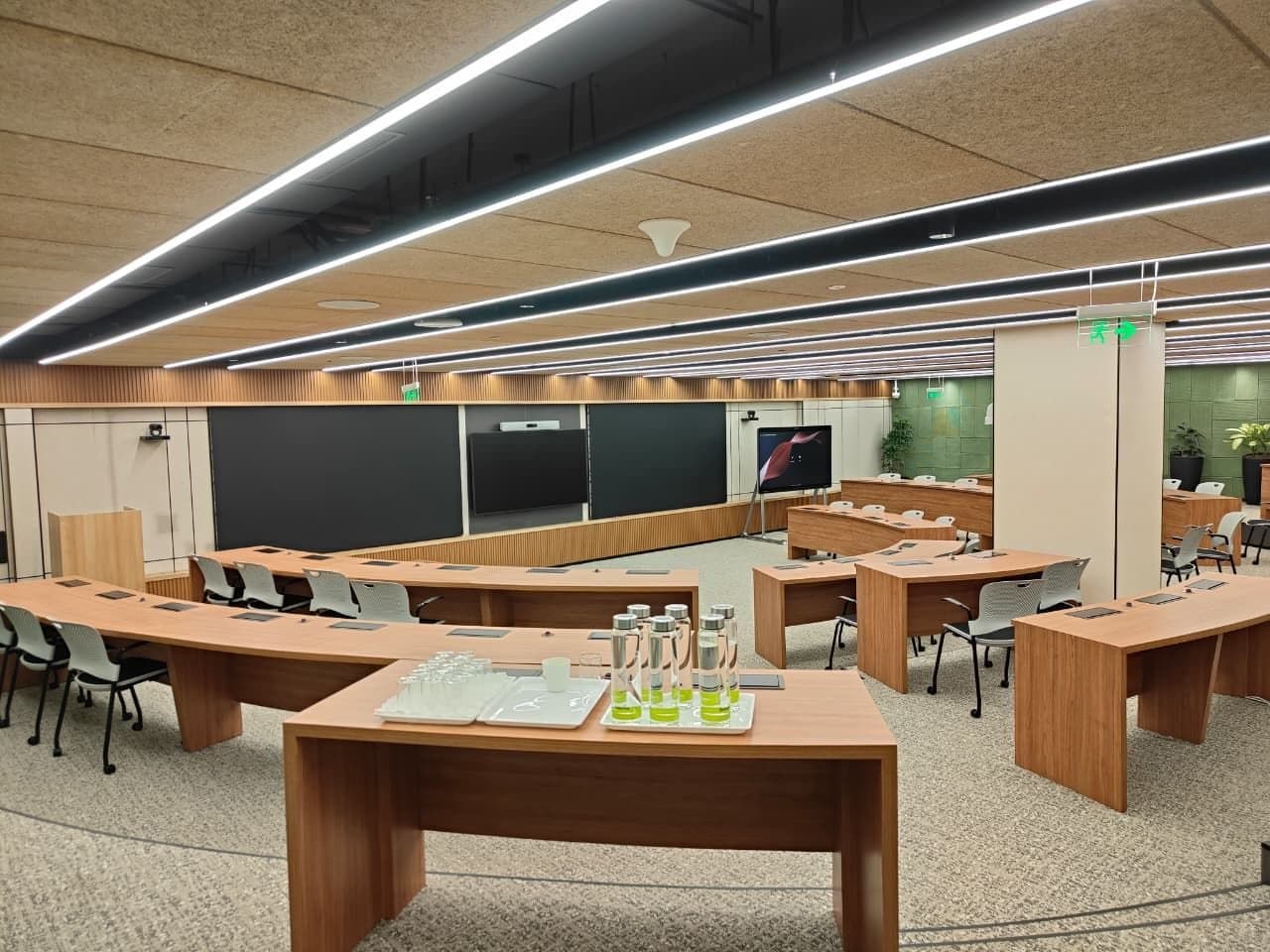 A Deloitte meeting room in Gurugram, long tables facing a wall screen.